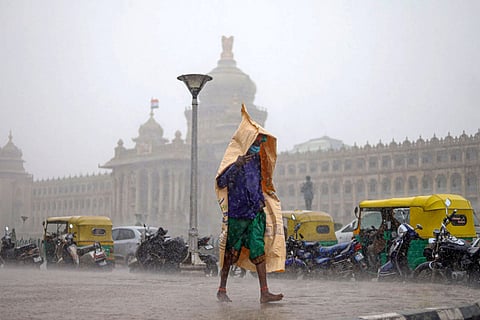 A file photo of a man taking cover amid rains in Benglauru