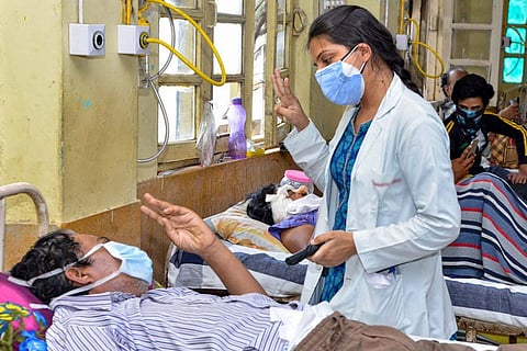 COVID-19 patient lying on bed and being treated by a lady doctor