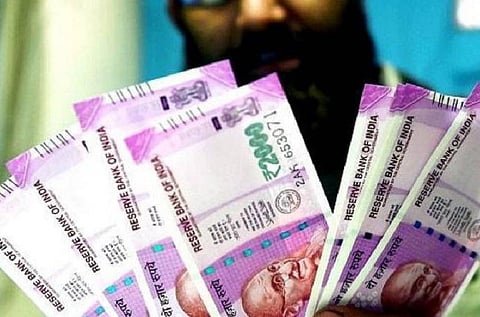 A man holding two thousand rupees notes.