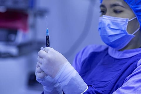 A health worker holding a syringe of COVID-19 vaccine