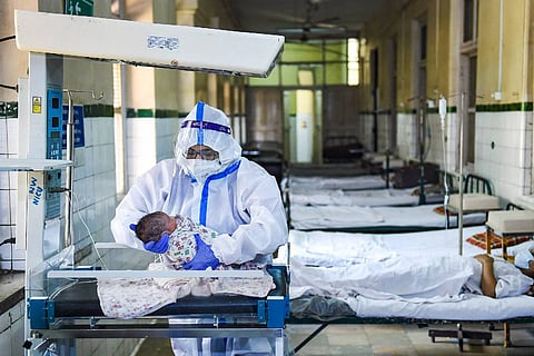A doctor in a PPE kit examining a newborn baby: Telangana hospital denies admission to pregnant woman with COVID, doctor suspended