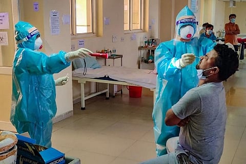 A health worker wearing PPE suit, mask and gloves collecting nasal swab from a man for coronavirus test