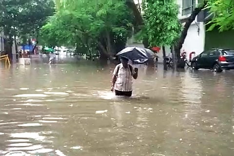 A man walking with an umbrella in a flooded street in Chennai