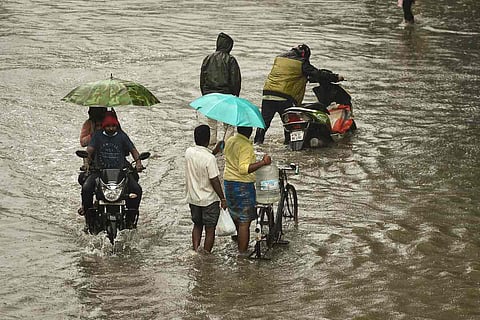 Commuters wade through a water-logged street following heavy rain, in Chennai