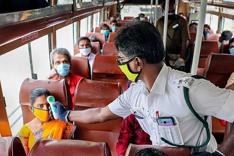 Employees of Coimbatore Transport Corporation check the temperature of passengers
