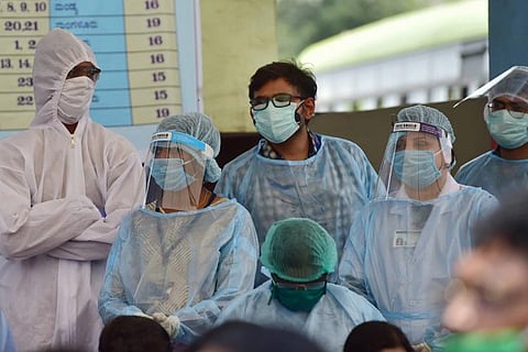Five people wearing PPE kits and face shields