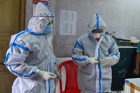 Two healthcare workers wearing PPE suits standing in a clinic
