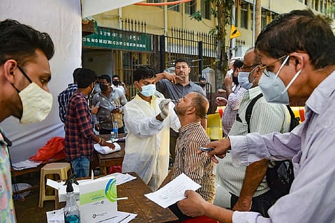 A health worker wearing mask and gloves collecting nasal swab from a man for coronavirus test