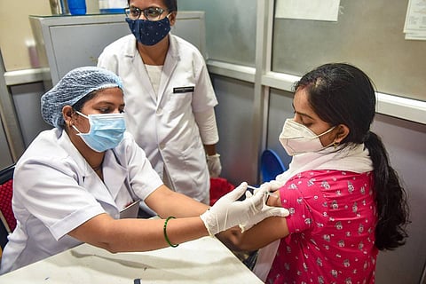 A woman receiving COVID-19 vaccine from a health worker