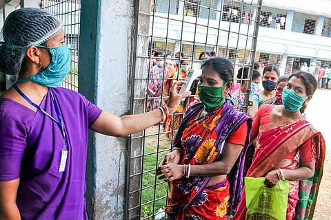Tamil Nadu local body polls: An election official checking the temperature of a voter during the polls