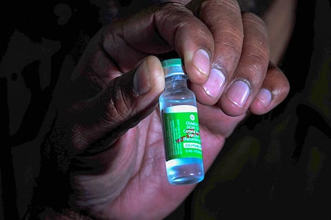 A health official shows a vial of Covishield vaccine