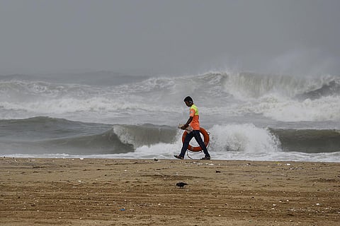 A lifeguard walks along the sea