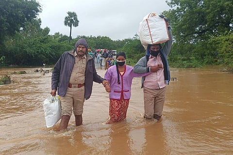 Nellore police helping a woman and man cross a flooded road