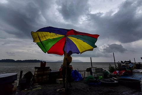 Cyclone representative: A fish vendor struggles to hold onto his umbrella against the fast blowing winds with dark clouds seen above