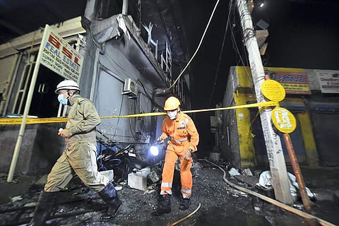 Rescue officials at the spot in Delhi where massive flames engulfed a building, killing at least 27 people