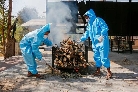 Frontline workers in personal protective equipment (PPE) arrange funeral pyre for Covid19 victim at a crematorium in Ahmedabad