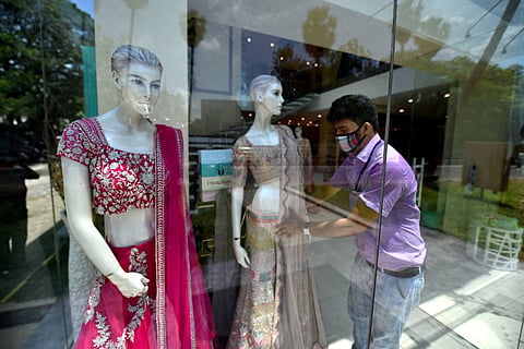 A worker in a garment store dressing up a mannequin