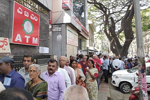 A long line of people waiting outside Sri Guru Raghavendra Sahakara Bank Niyamitha