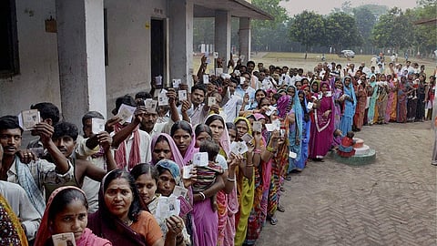 Men and women hold up their voter ID cards as they queue to vote