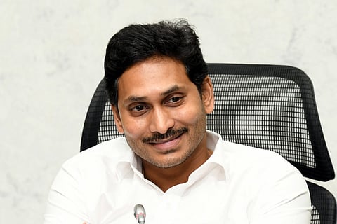 CM Jagan dressed in a white shirt smiling looking away from the camera
