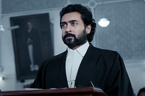 Screengrab from the movie Jai Bhim showing Suriya dressed up as a lawyer in a courtroom.
