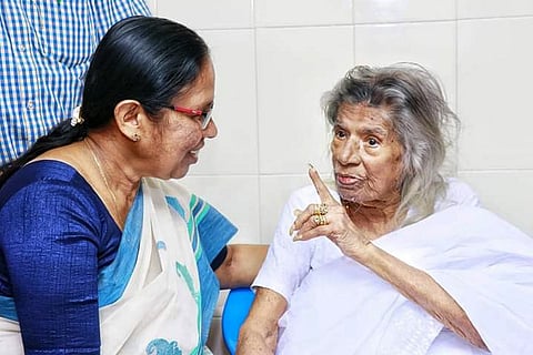 CPI(M) leader KK Shailaja in a white and blue saree speaking to Gouri Amma