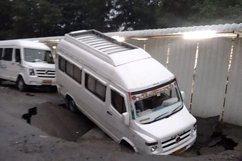 A van almost completely fallen into a giant hole after a road caved in at Chennai due to heavy rains