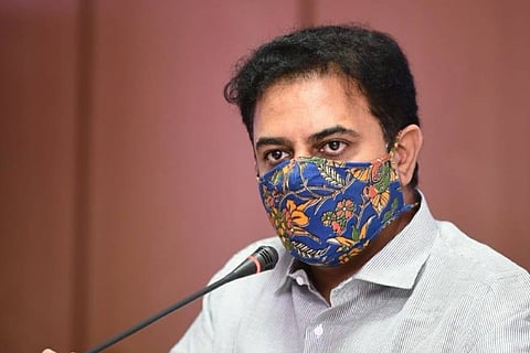 KTR wearing a white shirt and blue printed mask addressing the media
