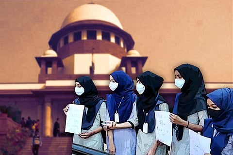Five hijab-clad students holding up signs with the Supreme Court of India in the background