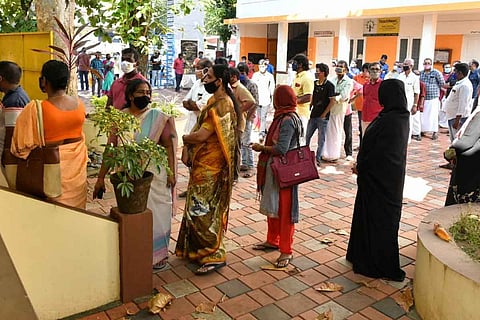 People standing in queue in front of polling booth