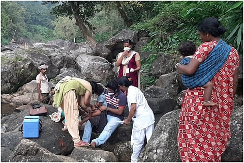 A kid in a tribal village being administrated injection on a huge rock
