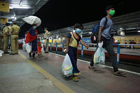 A migrant labourer along with a girl child walking in a railway station