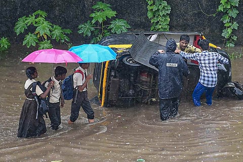 Representative image of school children wading through a flooded road