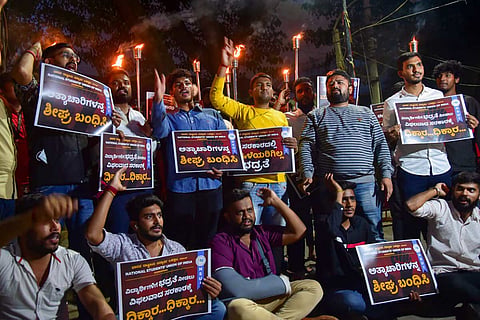 Members of NSUI hold placards and torch light and raise slogans during a protest against the state government alleged inaction regarding Mysuru gangrape incident in Bengaluru