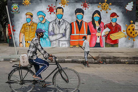 People in front of a mural of COVID warriors
