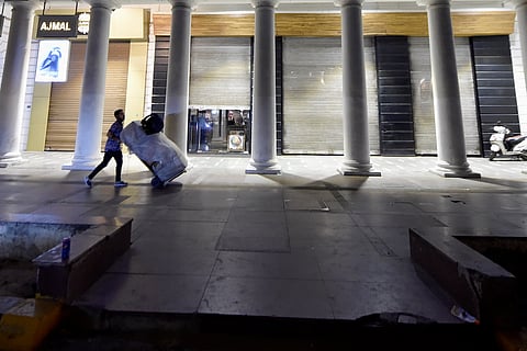 A man pushes a trolley in a deserted space in New Delhi at night owing to the night curfew