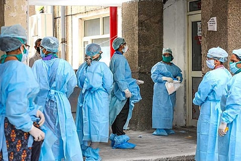 Doctors wearing blue PPE kit in a hospital building oustide a room