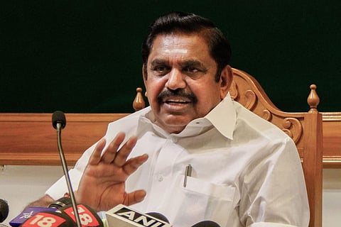 File image of Edappadi Palaniswami sitting at his desk wearing a white shirt and addressing the media