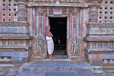 A priest standing outside the temple facing away from camera