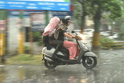 Commuters driving through rain on a two-wheeler