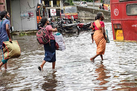Rains: Commuters wade through a waterlogged road after heavy rain
