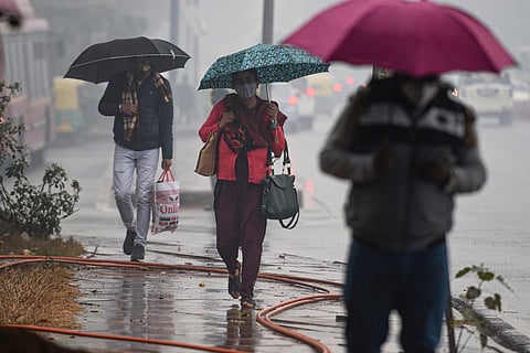 Commuters hold umbrellas as they walk in the rain