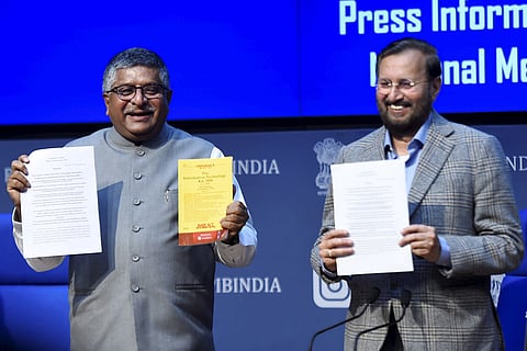 Ravi Shanker Prasad and Prakash Javadekar holding up documents to show the cameras