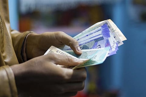 Person counting money, only hands and currency notes visible, image taken from the left