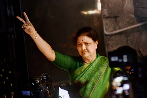 VK Sasikala in a green sari holding up two fingers