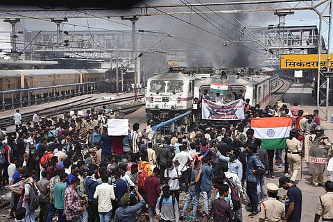 A heavy group of protestors staging protest in front of a train as the police stand near.