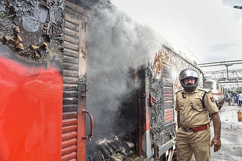 A policeman standing next to a burnt coach