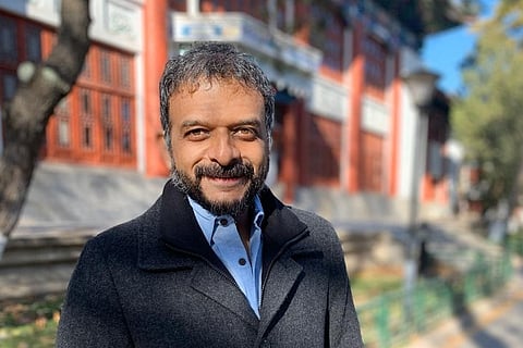Musician TM Krishna wearing a grey blazer and smiling into camera