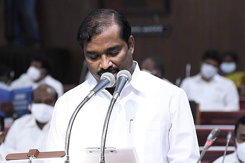 TVK chief in a white shirt speaking before a mic in assembly