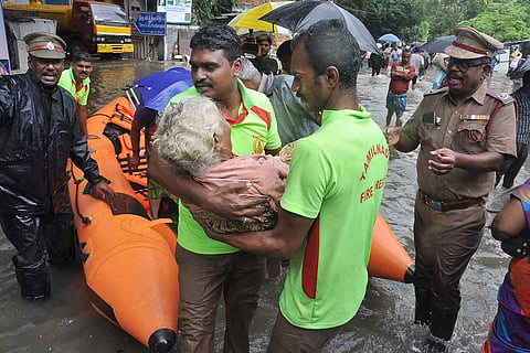 Fire department personnel rescuing an old woman amid floods in Tamil Nadu